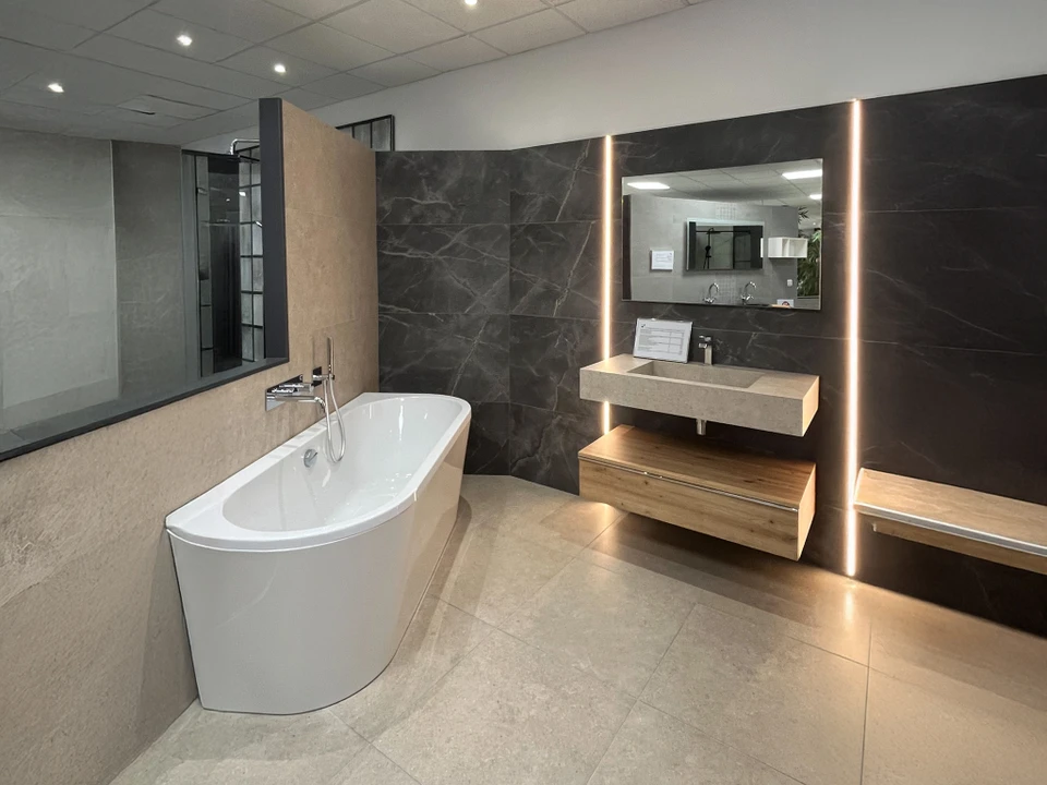 Salle de bain moderne spacieuse avec baignoire &icirc;lot blanche, douche &agrave; l'italienne avec paroi vitr&eacute;e, vasque suspendue et rangements muraux