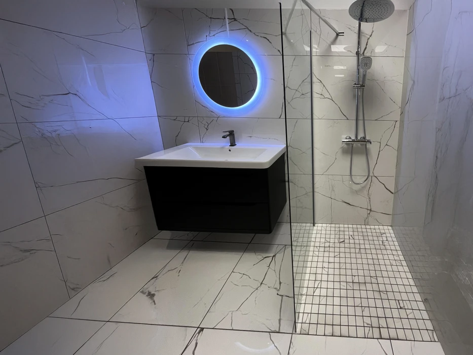 Cuisine moderne avec îlot central, façades blanches laquées sans poignées et plan de travail gris anthracite